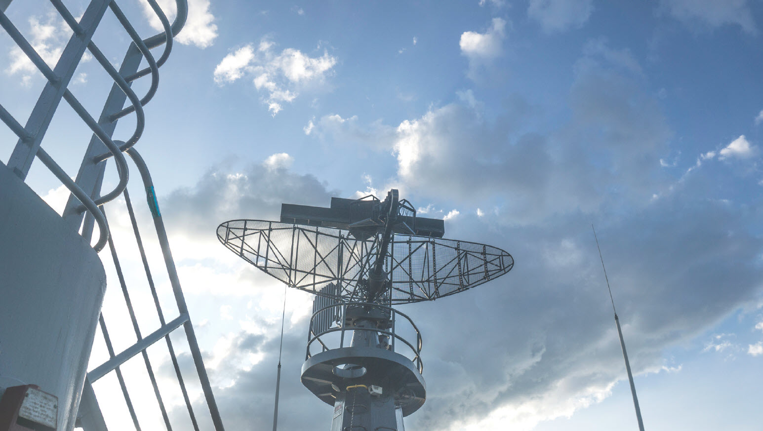 The top of an engineering ship is shown against a blue sky with white clouds.