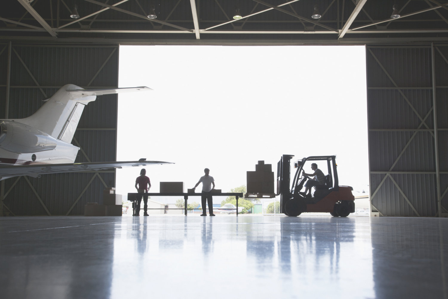 Workers, boxes and forklift in hangar