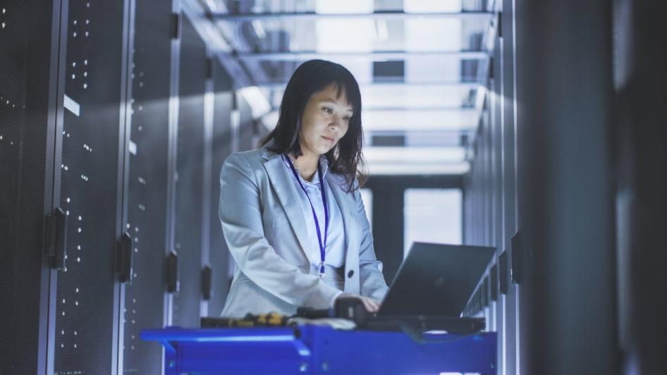 Woman working on laptop in data center